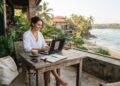 Digital nomad working remotely on a laptop at an open air café on Sri Lanka’s tropical south coast.